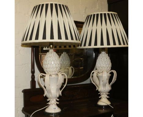 A pair of white ceramic based pineapple tablelamps raised on marble plinths.