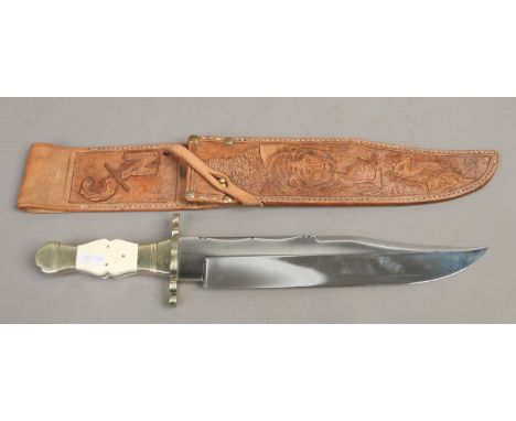 A large Bowie knife on tooled leather scabbard. With ivorine scales, brass cross guard and file work blade with dipped edge, 