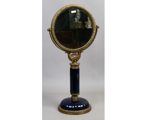 A circular bevel edge mirror suported on a brass and ceramic stand