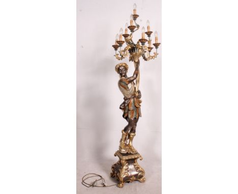 A parcel gilt and silvered floorstanding large figure of a Blackamoor holding a cornucopia shell aloft that has ten branches 