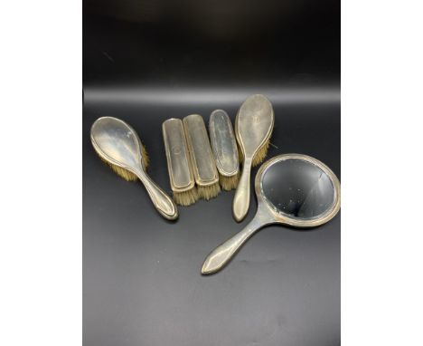 A silver backed hand mirror and three silver back brushes with engine turned decoration, Birmingham 1924; together with two s
