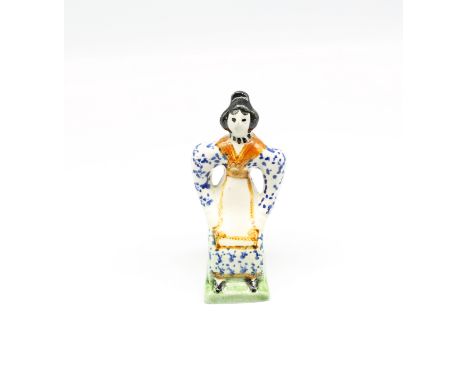 A small Prattware figure of a seated lady, painted in underglaze colours of blue, ochre, black and green.  Circa 1800. Size. 