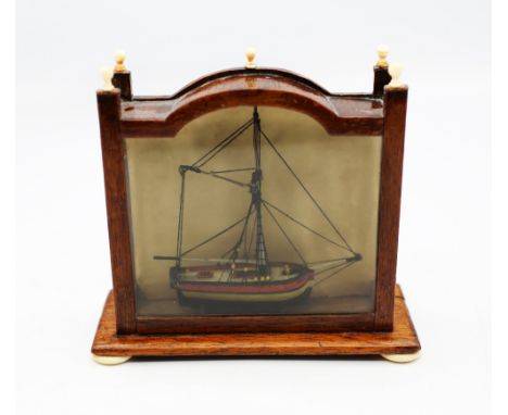 A late Georgian era miniature model of a a sailing boat, housed in a purpose built glass and mahogany case. The vessel is sim