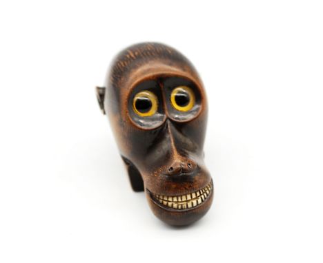 An early 19th century carved ebonised sycamore snuff box in the form of an exaggerated monkey head, with large circular glass