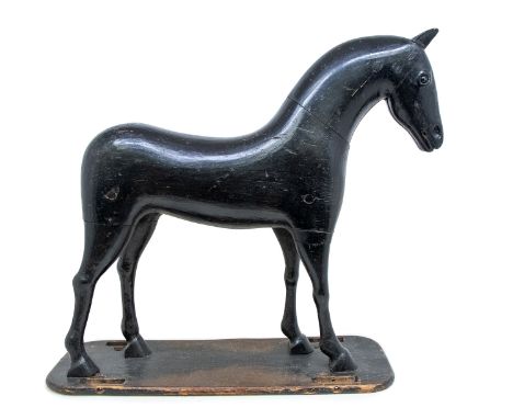  A late 19th / early 20th century ebonised wooden Folk Art model of a horse, on a oblong base, originally would have been a p