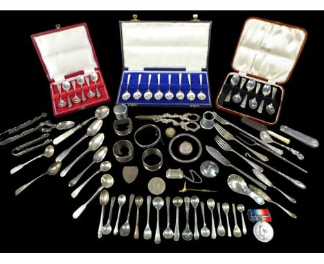 A collection of silver items, including caddy spoons, tongs, various other flatware, napkin rings, three cased sets of teaspo