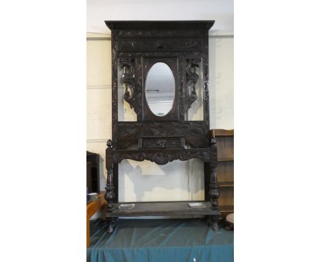 A Large Late Victorian Carved Oak Hall Stand with Glove Drawer, Oval Mirror, Carved Dragon Mounts and Stretcher Shelf with Me