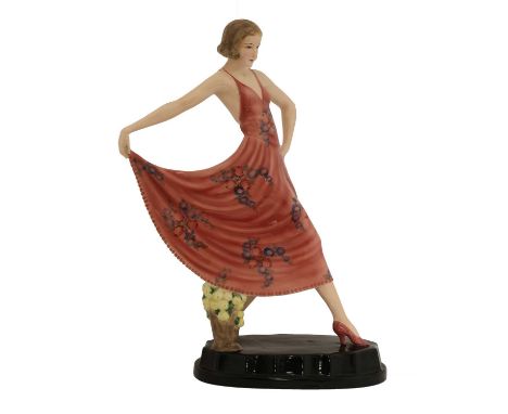 A Goldscheider pottery figure of a lady,designed by Josef Lorenzl, striking a pose holding her pink and floral decorated dres