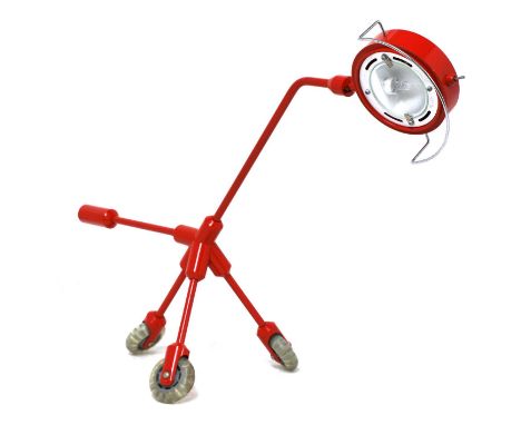 A contemporary red desk lamp,raised on three wheels, 67cm wide42cm highCondition report: Needs rewiring. some enamel wer to t