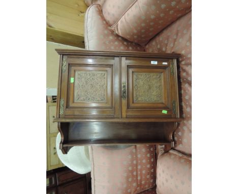 A late Victorian mahogany wall cabinet having shaped top and carved panel doors