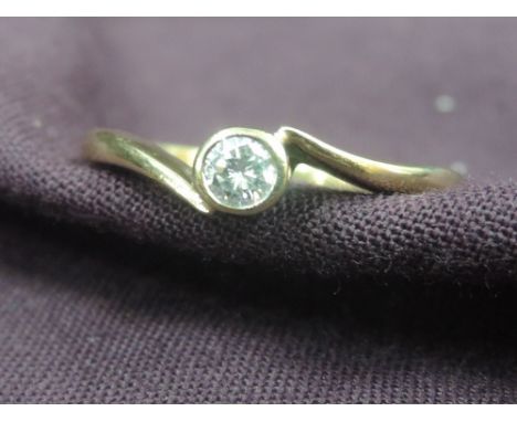 A lady's dress ring having a diamond solitaire in a collared mount to crossover shoulders on a 9ct gold loop,  size K