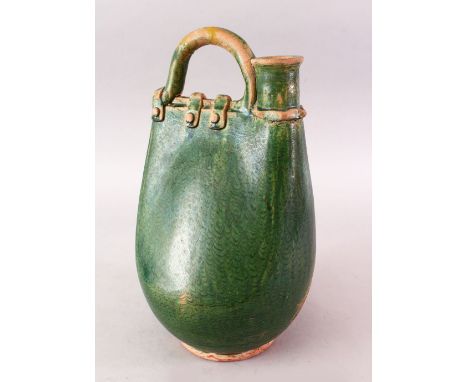 A CHINESE TANG DYNASTY GREEN GLAZED POTTERY POWDER FLASK SHAPED JUG, in the form of a stylized leather powder flask, 36cm hig