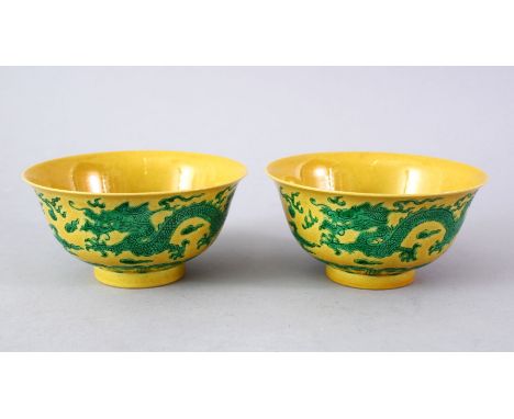 A GOOD PAIR OF CHINESE YELLOW GROUND DRAGON BOWLS, the side of the bows decorated with scenes of dragons chasing the flaming 