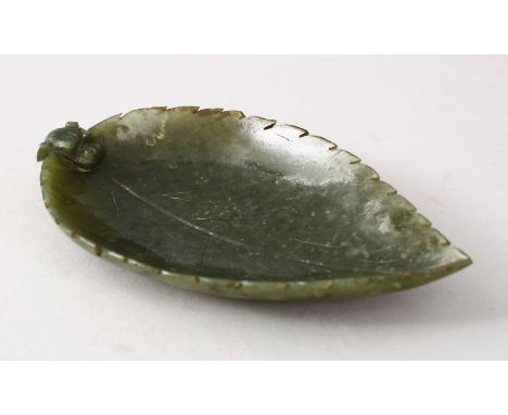 AN EARLY 20TH CENTURY CHINESE CARVED JADE BRUSH WASHER IN THE FORM OF A LEAF, with a lion dog head peering over the leaf, 18c