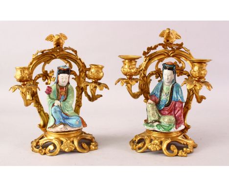 A GOOD PAIR OF 19TH CENTURY FAMILLE ROSE PORCELAIN FIGURES OF GUANYIN ON ORMOLU MOUNTED CANDLESTICK BASES, the figures decora