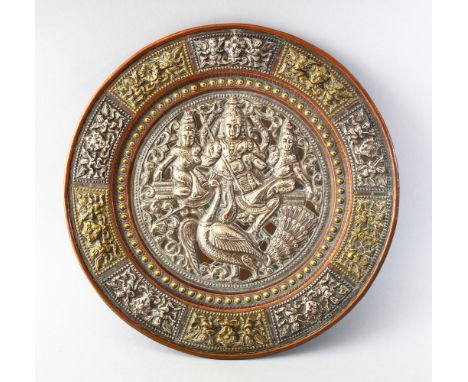 AN INDIAN TANJORE SILVER OVERLAID DISH, the central panel depicting three figures and a bird, the outer edge with panel borde
