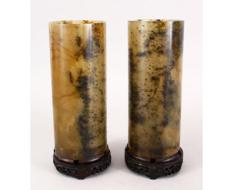 A PAIR OF 19TH / 20TH CENTURY CHINESE CARVED JADE CYLINDRICAL VASES, mounted to hardwood stands, 23.5cm high.