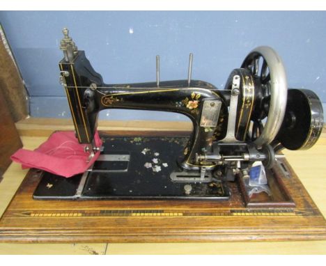 A vintage sewing machine with case and key with floral detail and marquetry inlay to base and case