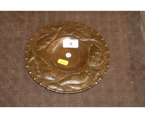An Arts & Crafts Newlyn planished copper dish with a band of sea fish and thumb pressed edged stamped 