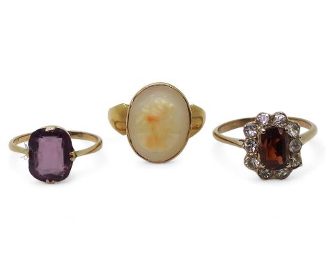 A 9ct gold cameo ring, size N, a 9ct purple glass ring, size J1/2, and a yellow metal garnet and clear gem set ring, size R, 