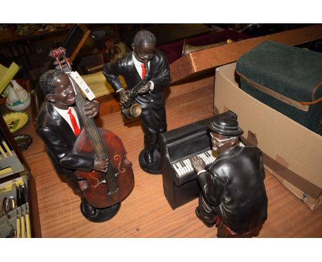 Three resin models of musicians, one playing saxophone; one playing a cello; and the other an organ/piano.
