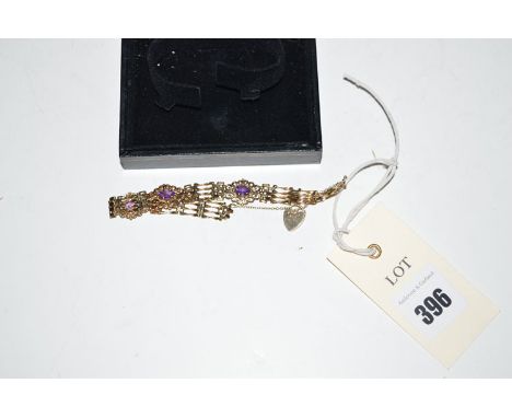 An amethyst set 9ct. yellow gold bracelet, the three main plaques set single oval facet cut amethyst amongst scrolls, held on