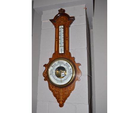 An aneroid barometer and thermometer within inlaid walnut case, decorated with leaf scrolls.