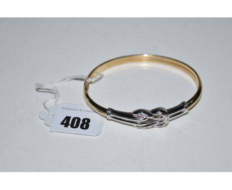 A white stone set yellow and white metal love knot pattern bangle, stamped '375', 11.5grms. gross.