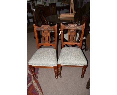 A set of six walnut salon chairs, each with carved leaf and branch designs upholstered in leaf scrolling material and raised 