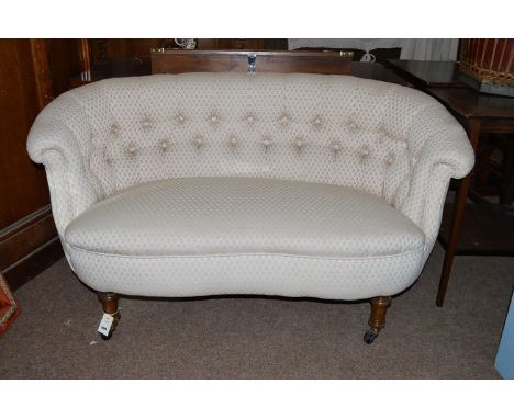 An early 20th Century button back stuff over settle, the upholstered back and seat raised on turned legs terminating on ceram