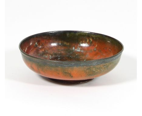 William Hair Haseler: An Arts and Crafts enamelled copper bowl in orange and mottled green on circular footed base, 21cm diam