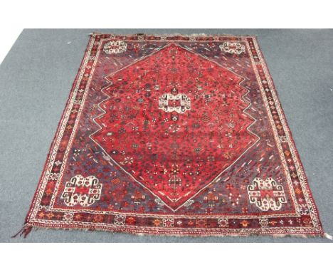 A Shiraz carpet with large central medallion on a red ground geometric field with medallion to each corner and floral figural