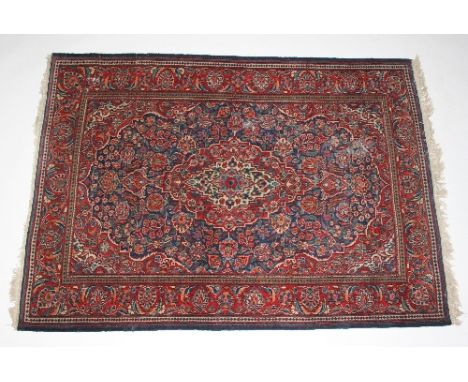 A Kashan rug with central medallion within a floral blue ground field and madder border, 190cm x 134cm Condition Report: The 