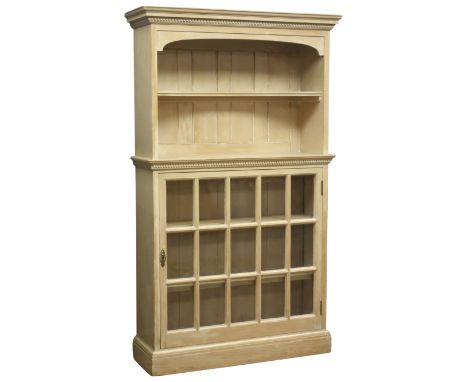 Pine bookcase display cabinet, projecting cornice with dentil frieze, shaped shelf above astragal glazed panel door on a plin