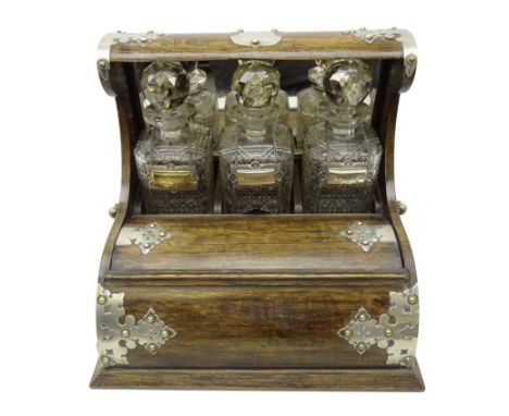 Early 20th century oak roll top tantalus, the three cut glass decanters with faceted stoppers and mirrored panel behind, silv