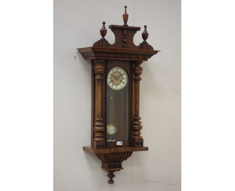 Early 20th century Vienna wall clock, mounted by triple urn finials, moulded cornice, glazed trunk door enclosing circular fa