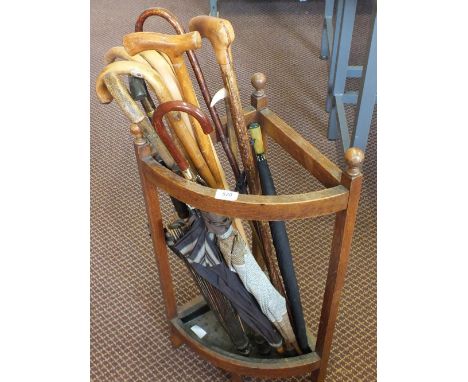 An oak stick stand containing sticks and brollies