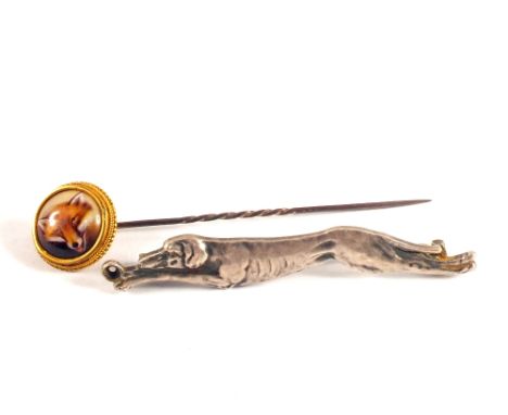 A yellow metal mounted stick pin with painted fox head plus a white metal brooch in the form of a running dog