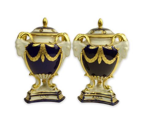 Pair Royal Dux Porcelain Cobalt and Parcel Gilt Covered Urns. Ram's head handles. Signed. Light wear and One with restoration