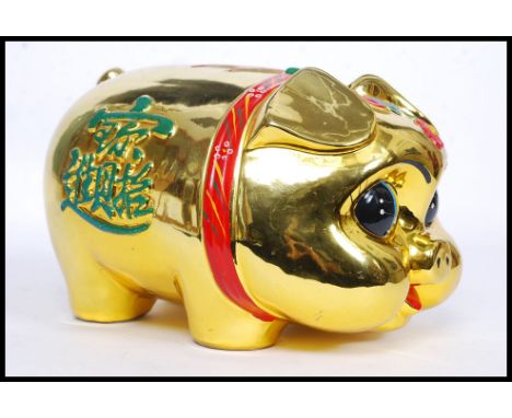 A 20th century Chinese ceramic statue money box in the form of a pig, heavy gold painting with oriental decoration. W28cm 