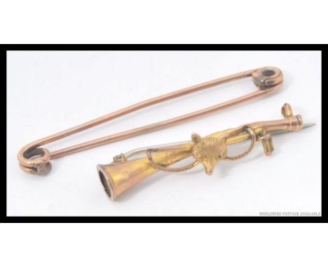 A 9ct gold hunting brooch depicting  a fox and riding crop over a hunting horn along with a gold metal pin badge