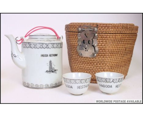 A 20th century Chinese ' Pagoda Restaurant ' tea for 2 service in whicker basket. Comprising teapot and 2 cups with decorativ