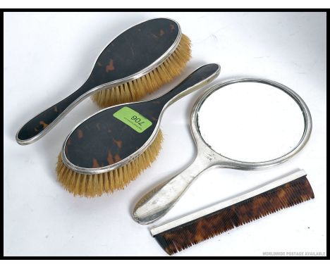 A decorative hallmarked silver and tortoiseshell part vanity set - to include mirror, comb and other pieces. 