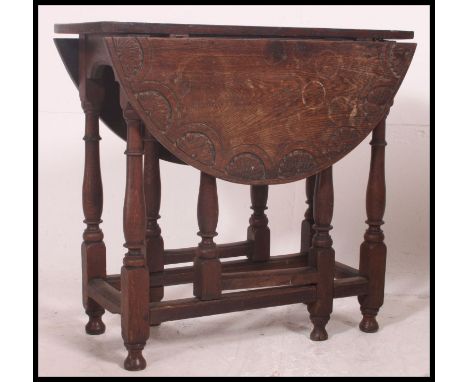 A 19th century oak gate leg drop leaf dining / occasional table. The carved oak table raised on gun barrel supports being peg