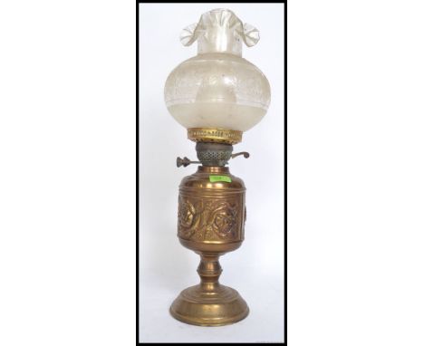 An ornate brass oil lamp having roses in repose to the body, original shade and glass flue. H58cm 
