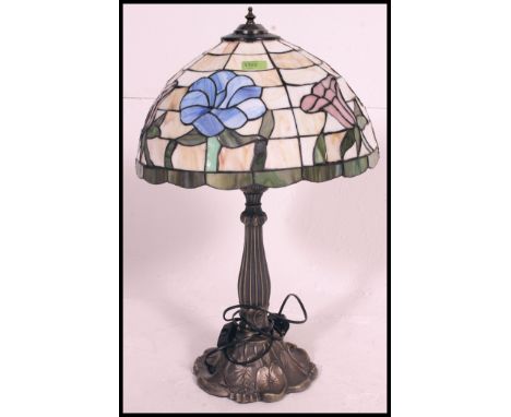 A Tiffany style lamp, having leaded coloured glass shade, raised on a Art Nouveau style base.
H67 x Shade width 40 cm 

