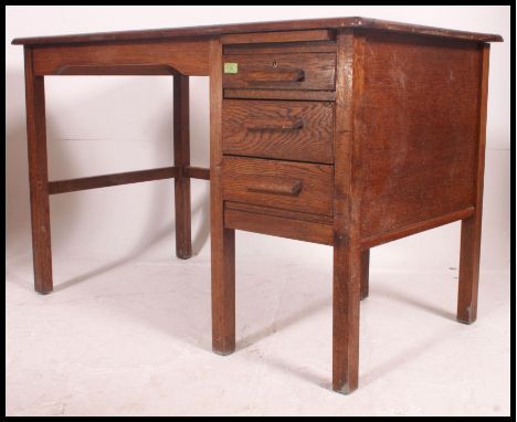 A mid century Air Ministry style oak desk with single pedestal of drawers flanked by open kneehole recess