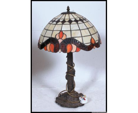 A large Art Noveau style Tiffany table lamp. The stained glass half moon shade over brass effect tree trunk stem.