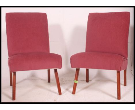 A pair of vintage mid century matching bedroom chairs, finished in a pink velour raised on splayed legs