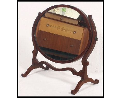 An Edwardian oval mahogany toilet swing mirror together with a mahogany fire screen with shelf to verso and a metamorphic gil